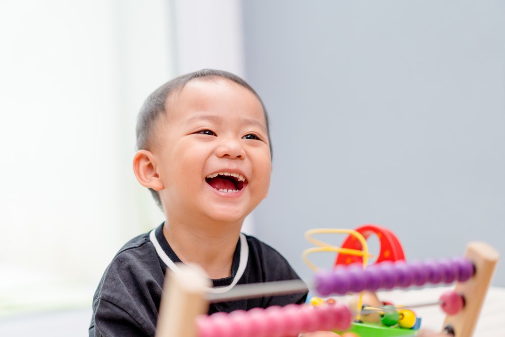 little boy laughing and playing with an abacus