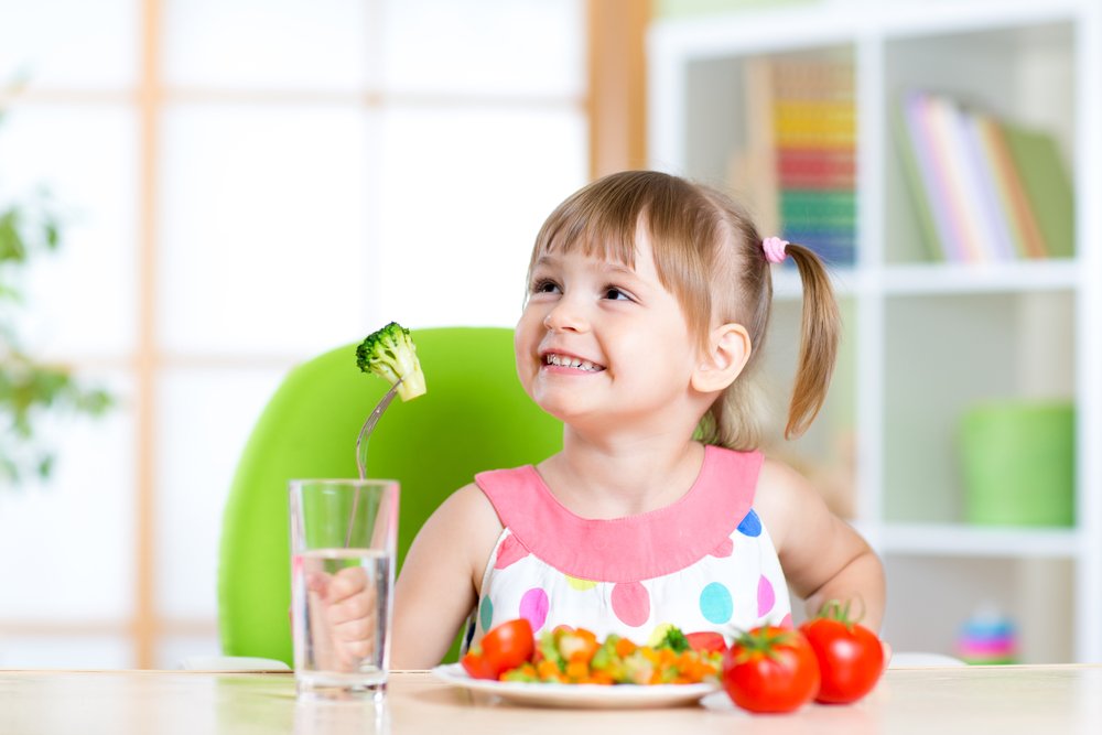 little girl eating vegetables by her own