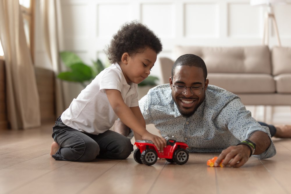 father and young son playing with cars at home