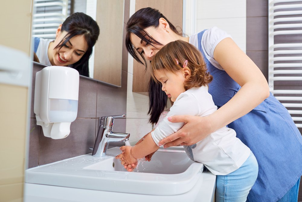 mother teaching her daughter how to wash her hands